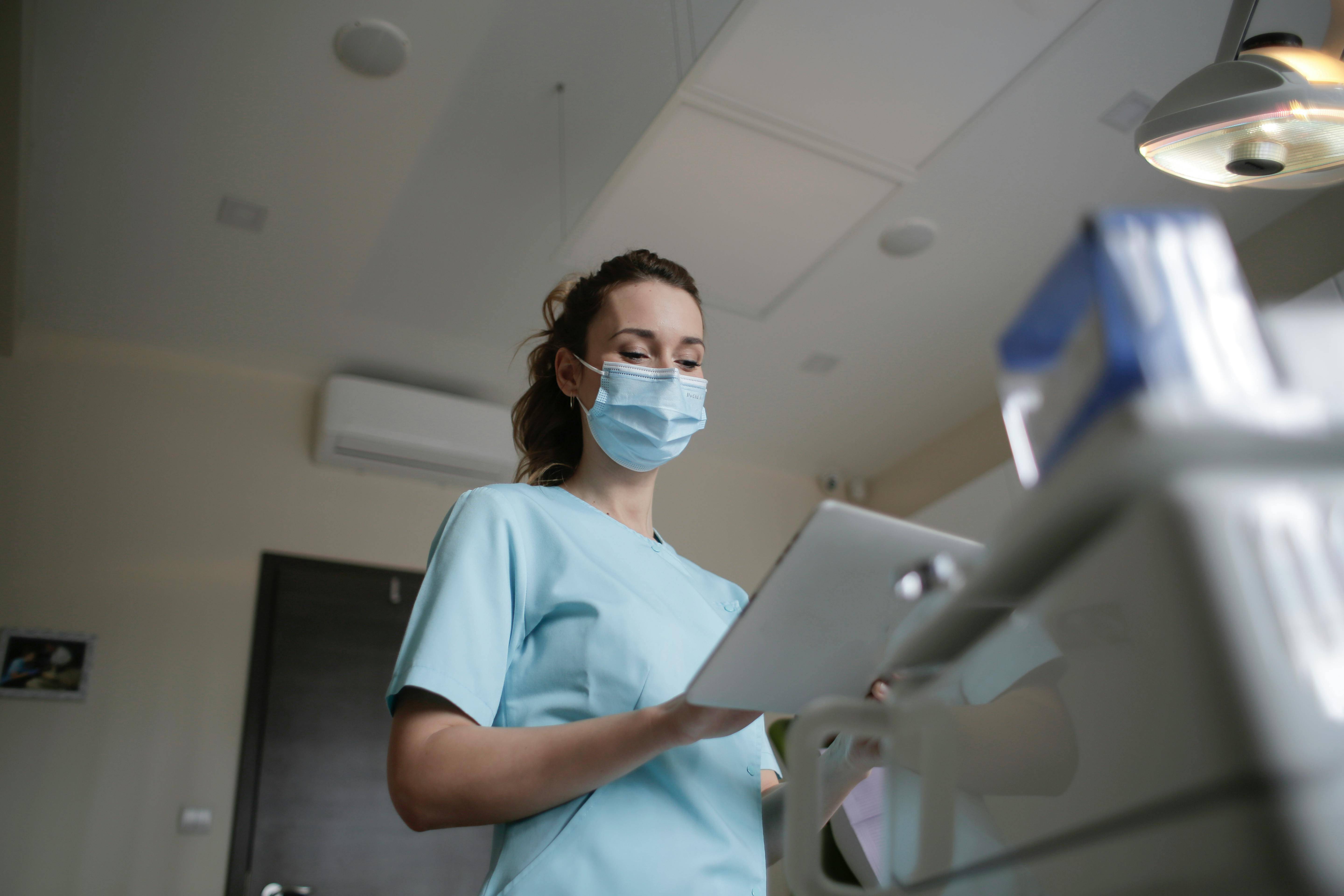 An image of a nurse wearing a face mask and doing something in the tablet