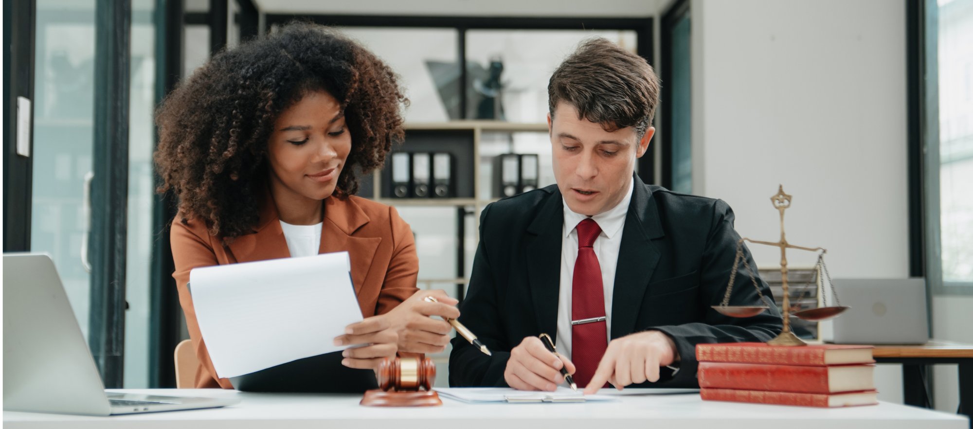 Two lawyers looking into paperwork sitting in a desk