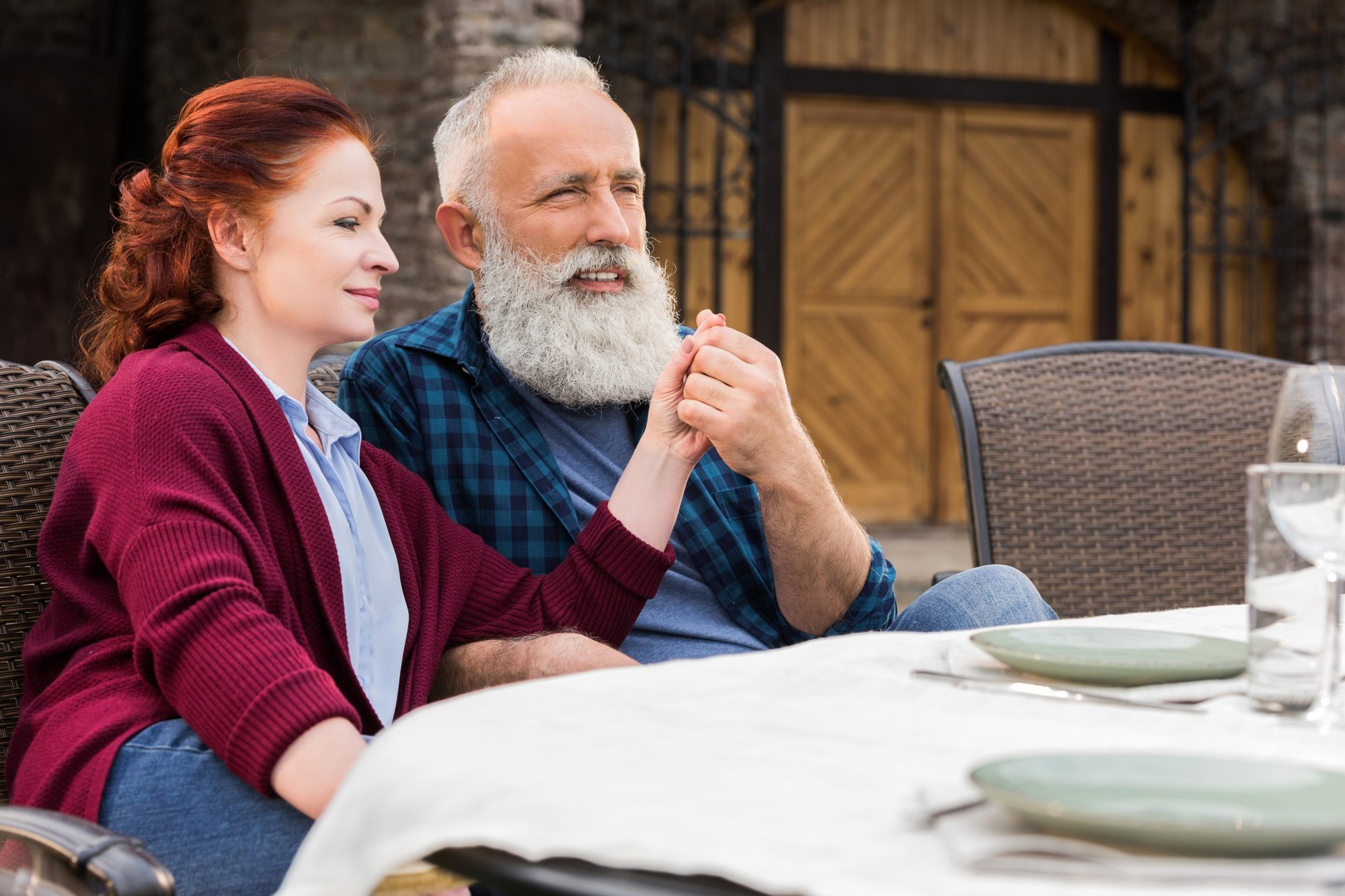 two seniors holding hands at a table